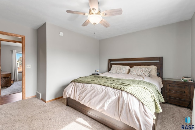 bedroom featuring visible vents, baseboards, a ceiling fan, and light colored carpet