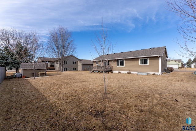 back of property featuring a detached garage, fence, and a deck