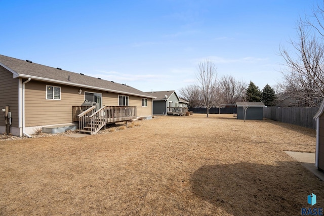 view of yard featuring a deck, a storage shed, an outdoor structure, and a fenced backyard