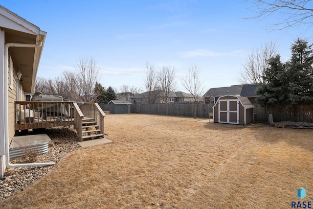 view of yard with a wooden deck, a fenced backyard, a residential view, a storage unit, and an outdoor structure