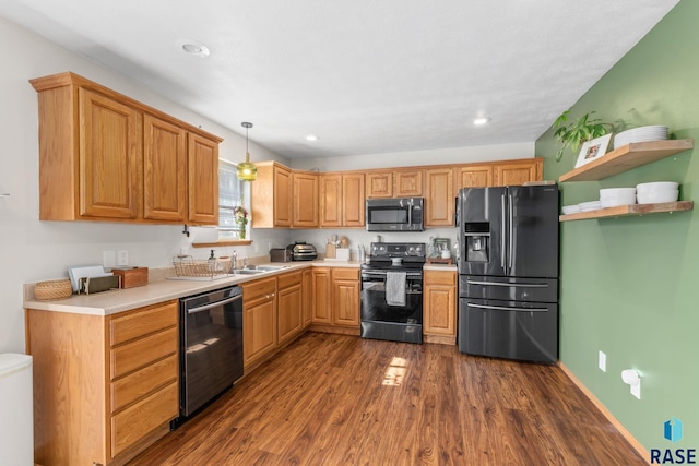 kitchen with dark wood-type flooring, a sink, light countertops, black appliances, and pendant lighting