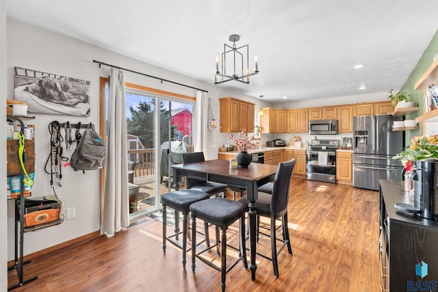 dining space with recessed lighting, baseboards, a notable chandelier, and light wood finished floors