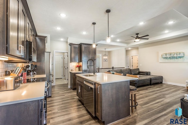 kitchen featuring an island with sink, open floor plan, decorative light fixtures, light countertops, and a sink