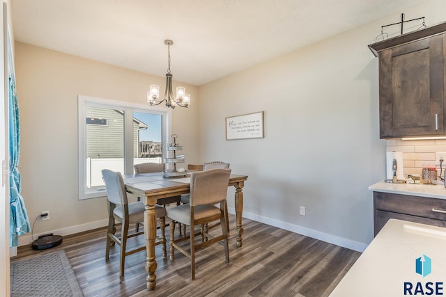 dining space featuring a chandelier, dark wood finished floors, and baseboards