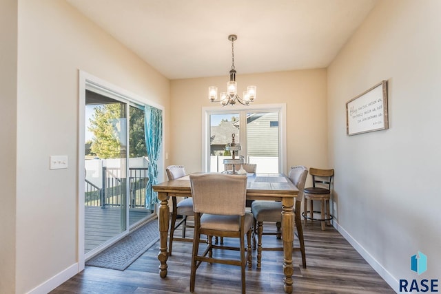 dining space featuring dark wood-style floors, a notable chandelier, and baseboards