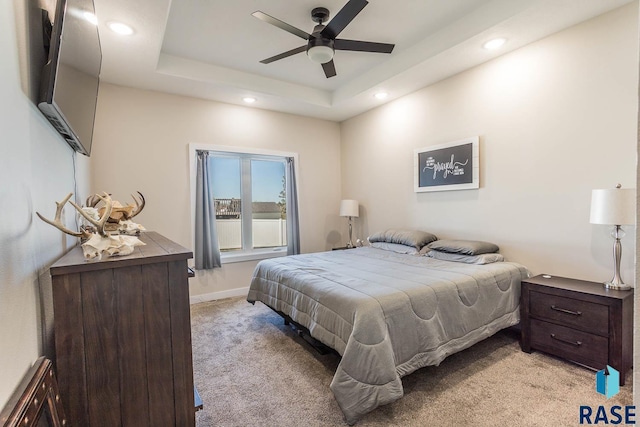 bedroom with ceiling fan, recessed lighting, light colored carpet, baseboards, and a tray ceiling