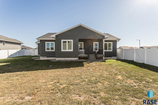 rear view of house with a fenced backyard and a yard