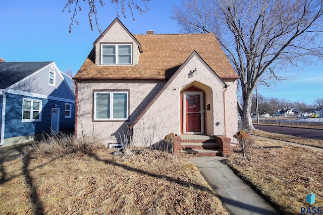 view of front of house with roof with shingles, a chimney, and stucco siding