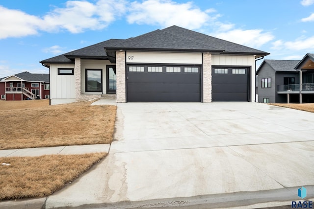 prairie-style home featuring driveway, board and batten siding, an attached garage, and roof with shingles