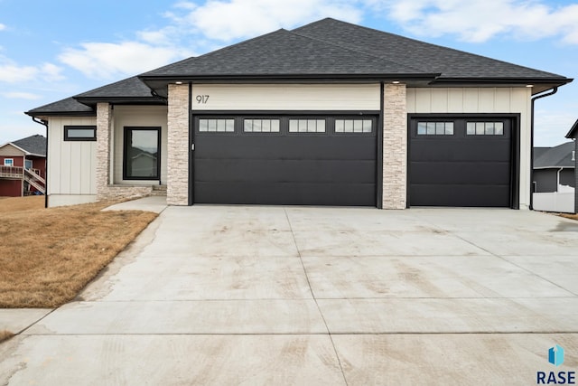 view of front of house with roof with shingles, board and batten siding, an attached garage, and driveway