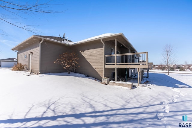 snow covered back of property with a wooden deck