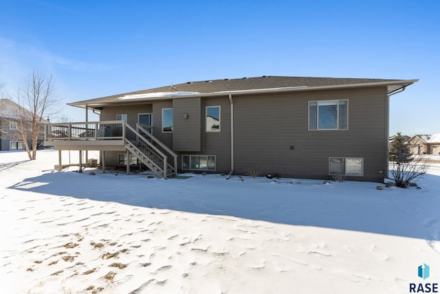 snow covered property featuring a deck and stairway