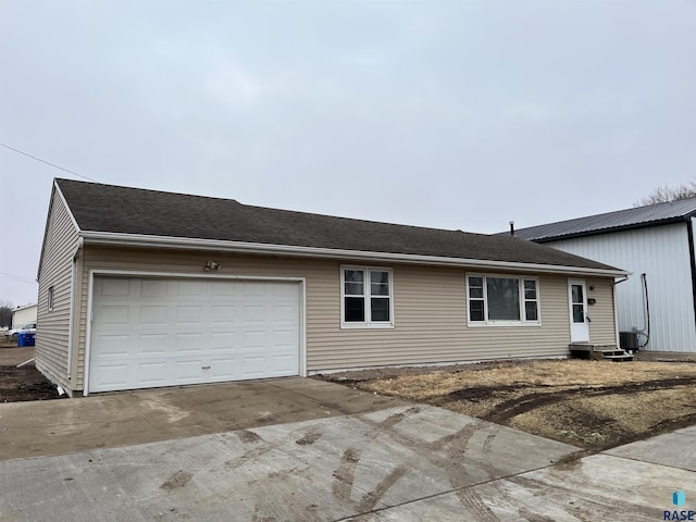 view of front of home with entry steps, concrete driveway, a shingled roof, and an attached garage