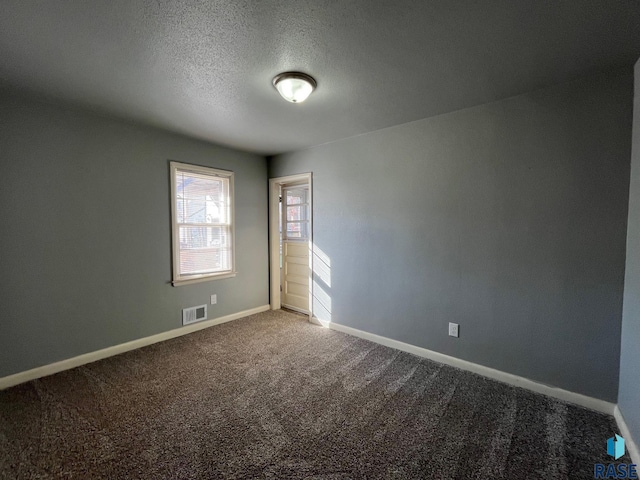 carpeted empty room featuring a textured ceiling, visible vents, and baseboards