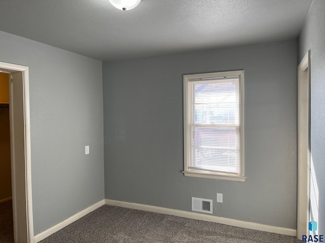 interior space featuring baseboards, visible vents, a textured ceiling, and carpet flooring