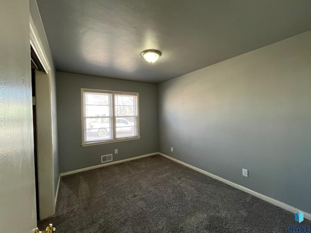 unfurnished room featuring dark carpet, visible vents, and baseboards