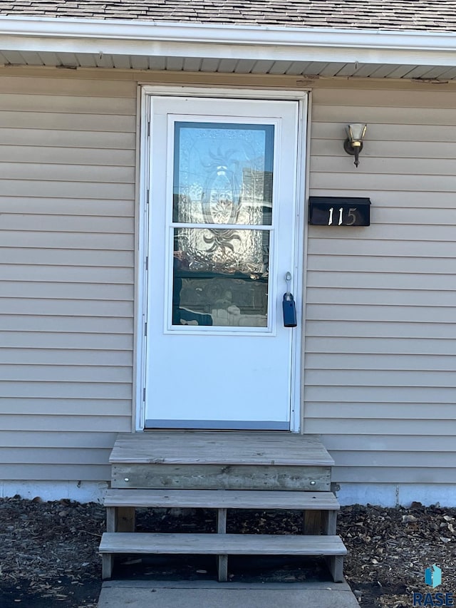 view of exterior entry with roof with shingles