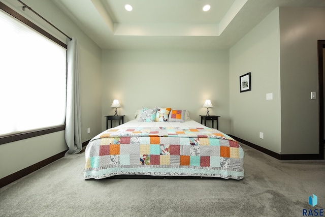 carpeted bedroom with recessed lighting, a raised ceiling, multiple windows, and baseboards