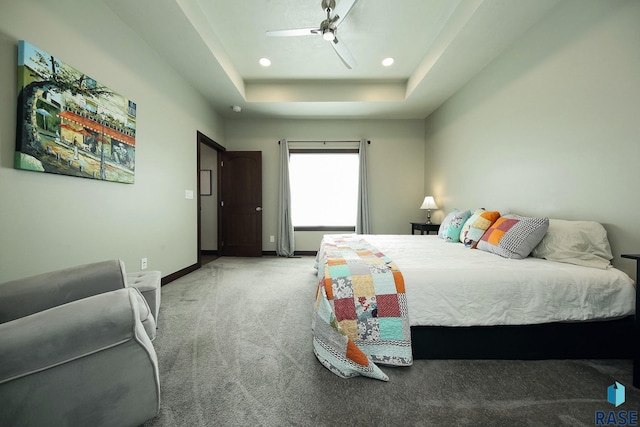 carpeted bedroom with ceiling fan, a tray ceiling, recessed lighting, and baseboards