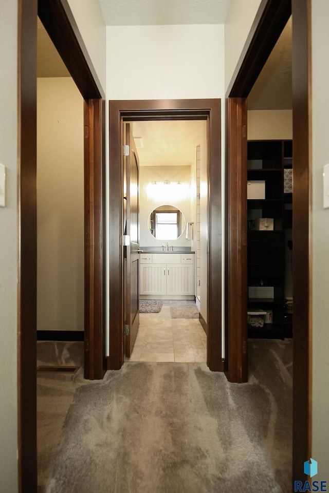 hall with light colored carpet and baseboards