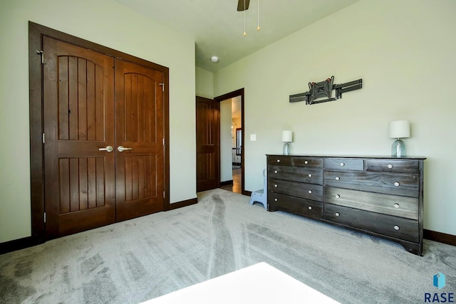 bedroom featuring light carpet, ceiling fan, baseboards, and a closet