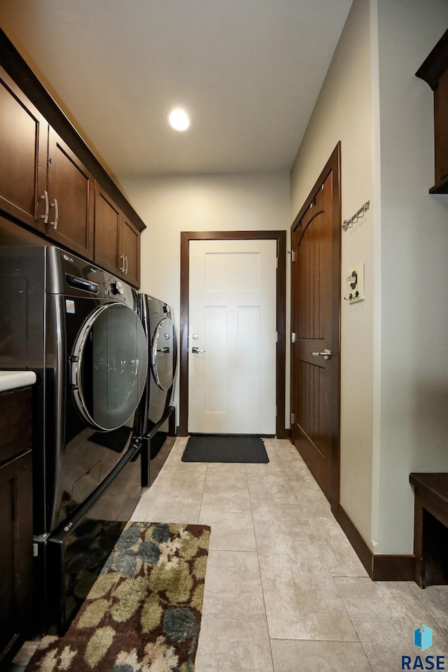 laundry area with cabinet space, washing machine and dryer, light tile patterned floors, and baseboards