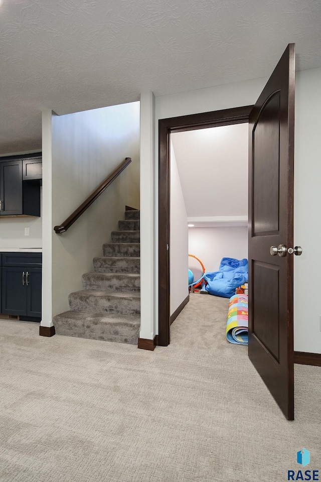 stairs with a textured ceiling, baseboards, and carpet flooring