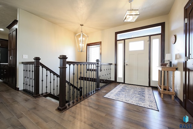 entrance foyer featuring dark wood-style floors, a chandelier, and baseboards