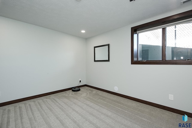 empty room with light carpet, visible vents, baseboards, a textured ceiling, and recessed lighting