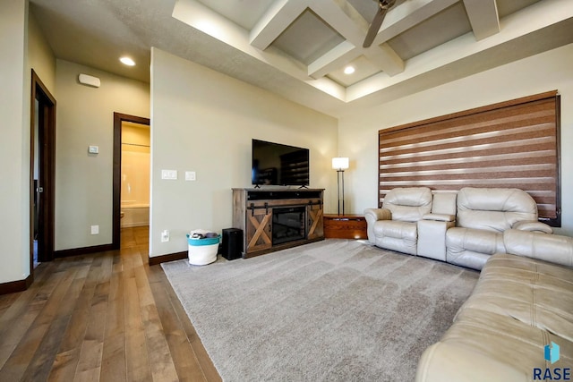 living room featuring wood-type flooring, a glass covered fireplace, coffered ceiling, beamed ceiling, and baseboards