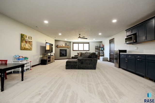 living room featuring light carpet, baseboards, a ceiling fan, and recessed lighting