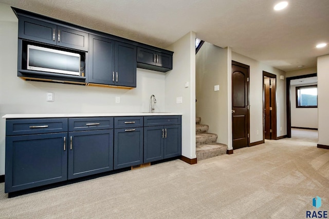 kitchen with recessed lighting, light colored carpet, light countertops, blue cabinets, and baseboards