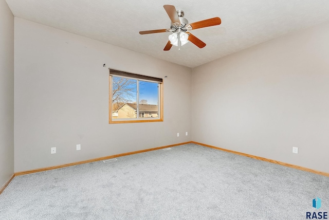 carpeted spare room with a textured ceiling, a ceiling fan, and baseboards