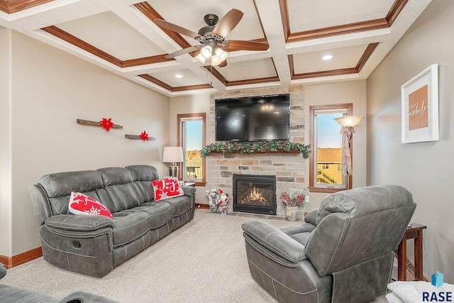 carpeted living room featuring crown molding, ceiling fan, a stone fireplace, coffered ceiling, and baseboards