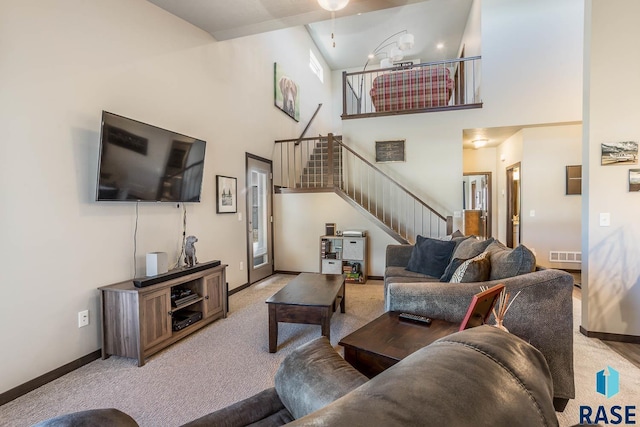 living room with a high ceiling, carpet flooring, visible vents, baseboards, and stairs