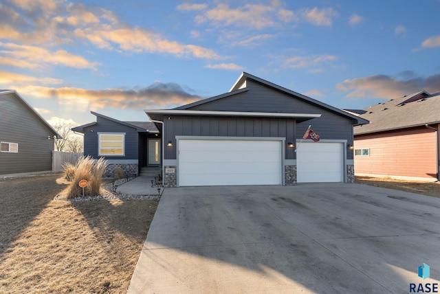 view of front of house featuring an attached garage, concrete driveway, board and batten siding, and stone siding