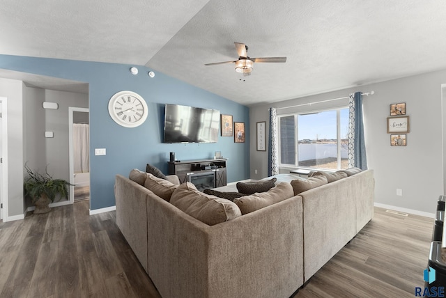 living room featuring a ceiling fan, vaulted ceiling, a textured ceiling, wood finished floors, and baseboards