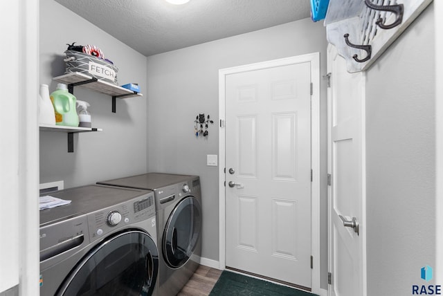 clothes washing area with a textured ceiling, washing machine and dryer, laundry area, dark wood-style flooring, and baseboards