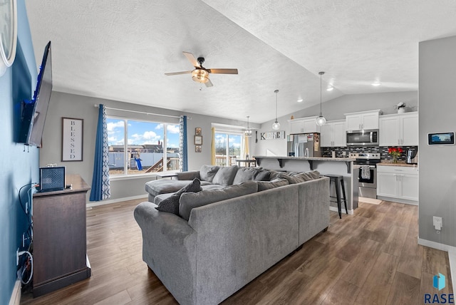 living area featuring lofted ceiling, ceiling fan, dark wood finished floors, and baseboards