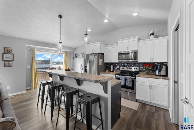 kitchen with a breakfast bar, a center island, hanging light fixtures, appliances with stainless steel finishes, and white cabinets