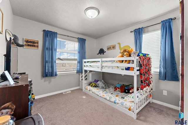 bedroom featuring a textured ceiling, carpet floors, visible vents, and baseboards