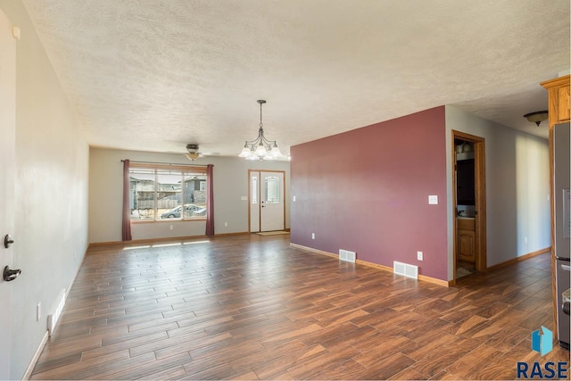 interior space with visible vents, dark wood finished floors, a textured ceiling, and baseboards