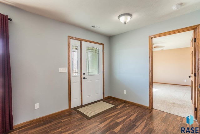 foyer with visible vents, baseboards, and dark wood finished floors