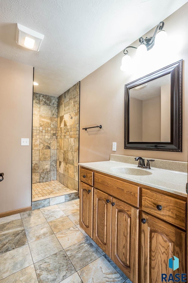 full bath with a textured ceiling, walk in shower, and vanity