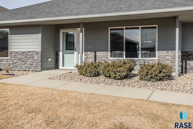 property entrance featuring stone siding and a shingled roof