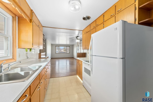 kitchen featuring open floor plan, light countertops, white appliances, and a sink