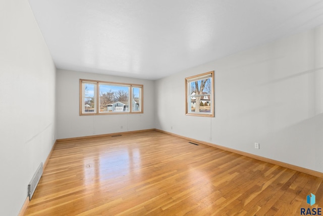 spare room featuring visible vents, light wood-style flooring, and baseboards