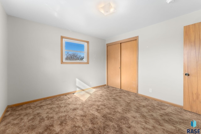 unfurnished bedroom with carpet floors, baseboards, and a closet