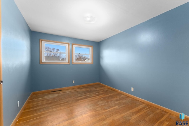 unfurnished room featuring baseboards, visible vents, and wood finished floors