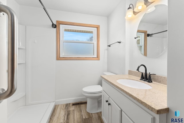 bathroom featuring visible vents, a shower, toilet, wood finished floors, and vanity